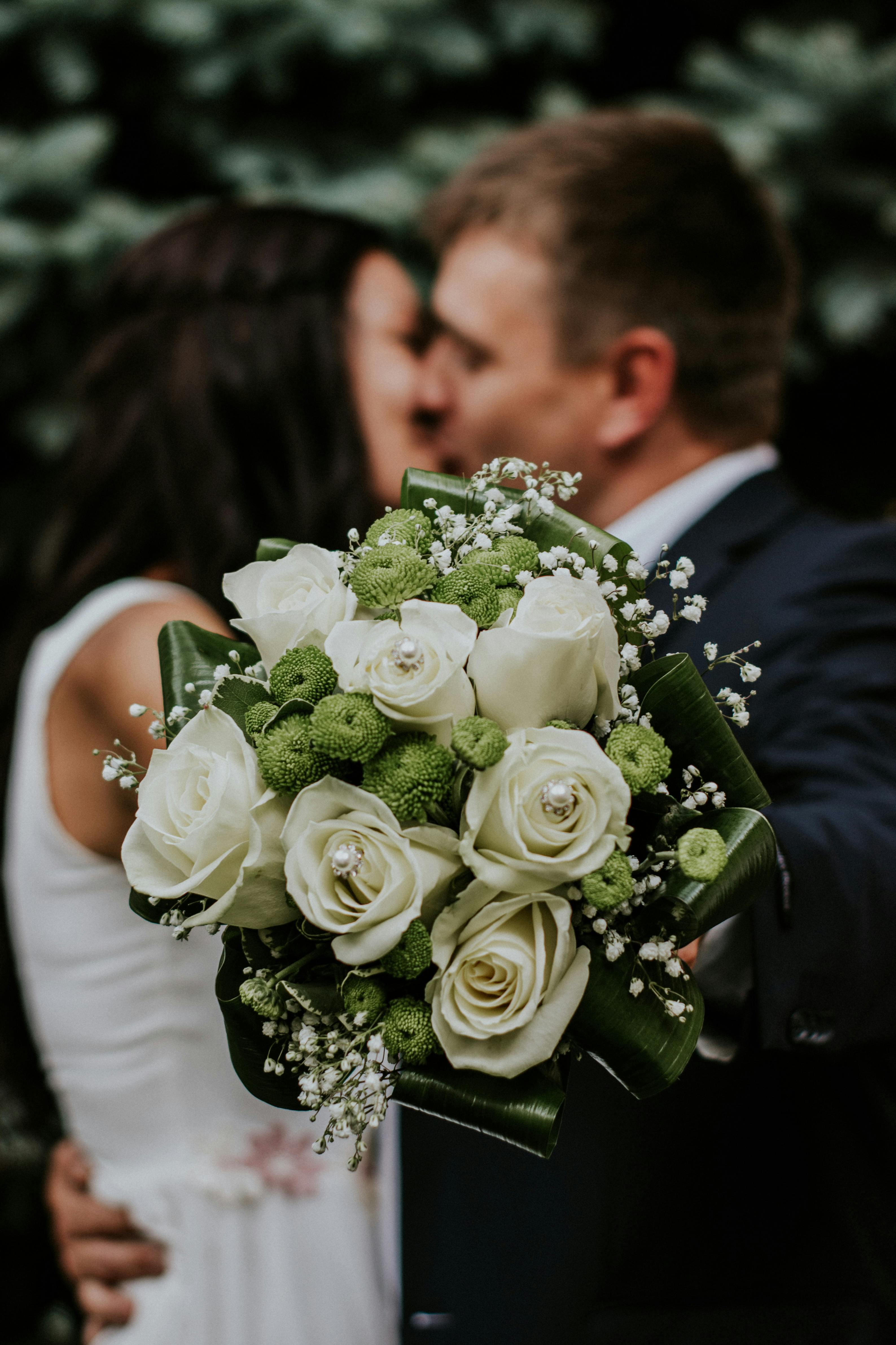 Couple holding bouquet towards camera