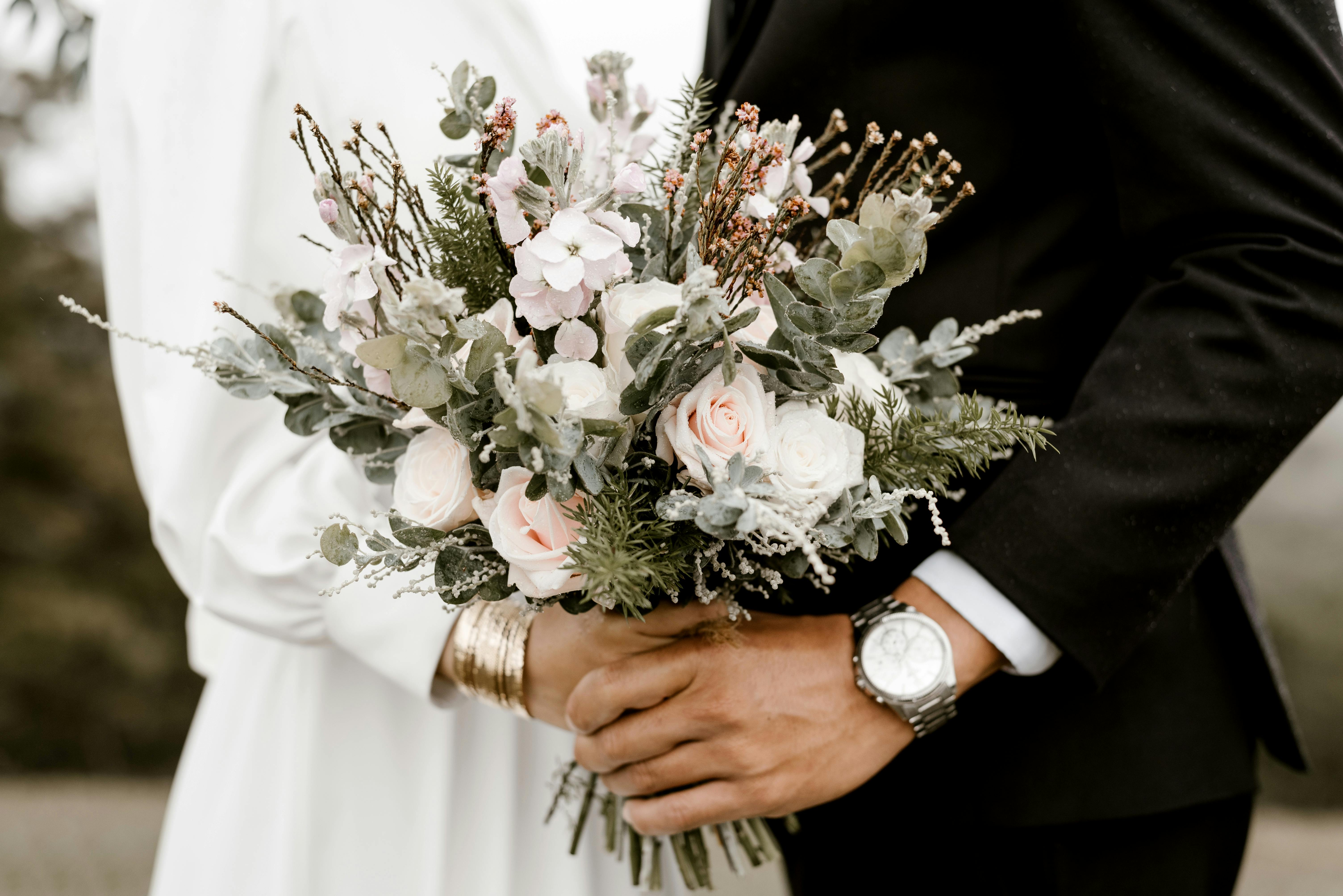 Couple standing on either side of bouquet